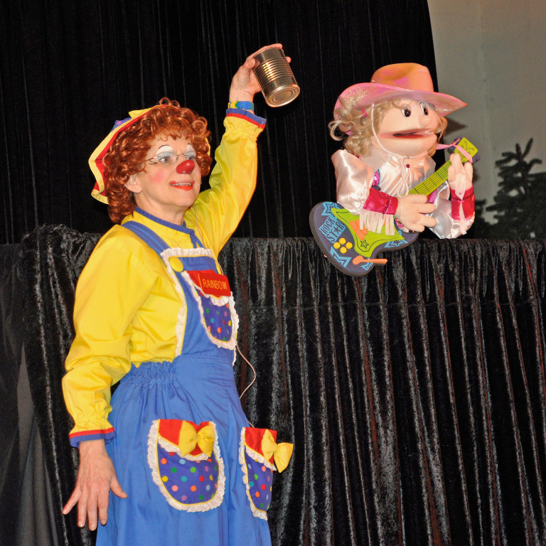 Rainbow holds a can while singing with a puppet sing