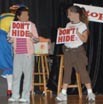 Two children hold signs that say "Don't Hide"